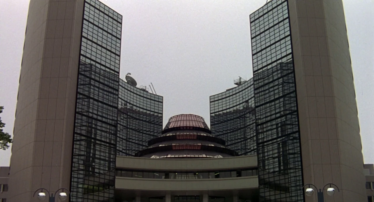 Godzilla vs. Mechagodzilla II (1993) movie still: establishing — A modern brutalist-style government complex features two curved glass towers…