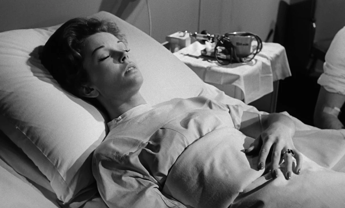 The 1,000 Eyes of Dr. Mabuse (1960) movie still: medium — A hospital bed with a patient lies in a clinical room. The woman rests on a white pillow…