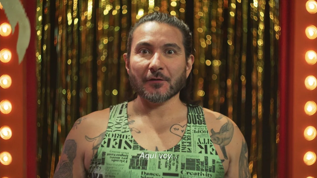 Felipe Avello: Doglover (2024) movie still: medium — A dressing room features vertical gold foil fringe curtains and rows of bright lightbulbs. A…