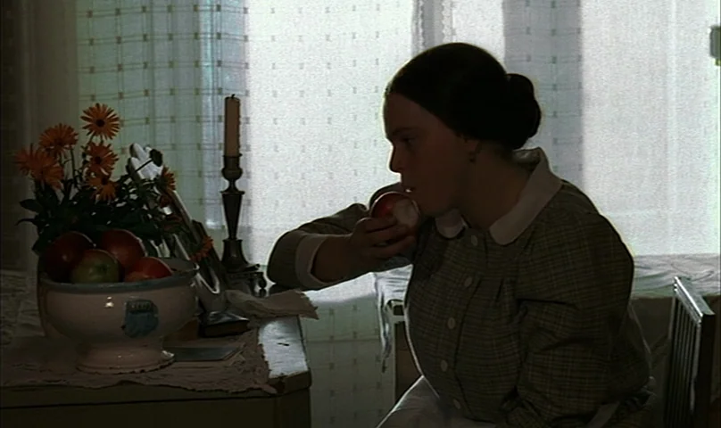 Cries and Whispers (1972) movie still: medium — An interior space features a table with a bowl of fruit near a window. A young woman sits in profile…