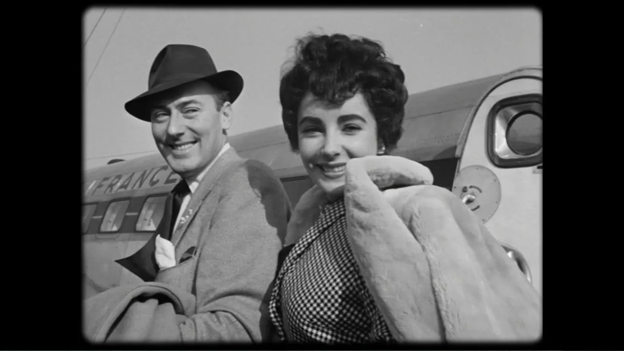 Elizabeth Taylor: The Lost Tapes (2024) movie still: medium — An outdoor airport tarmac shows an Air France plane in the background under daylight.…