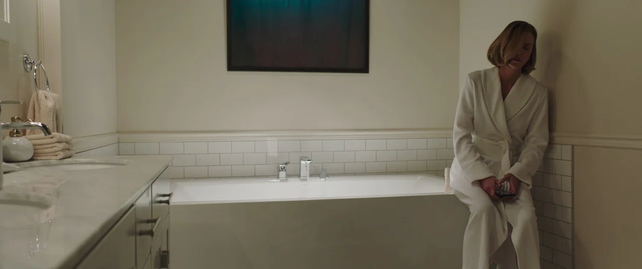 Long Shot (2019) movie still: medium — A clean, modern bathroom features white subway tiles, a marble vanity, and deep walls. A woman in a white…