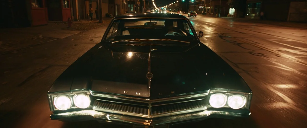 Judas and the Black Messiah (2021) movie still: medium — A classic black muscle car travels down a deserted city street at night. The vehicle…