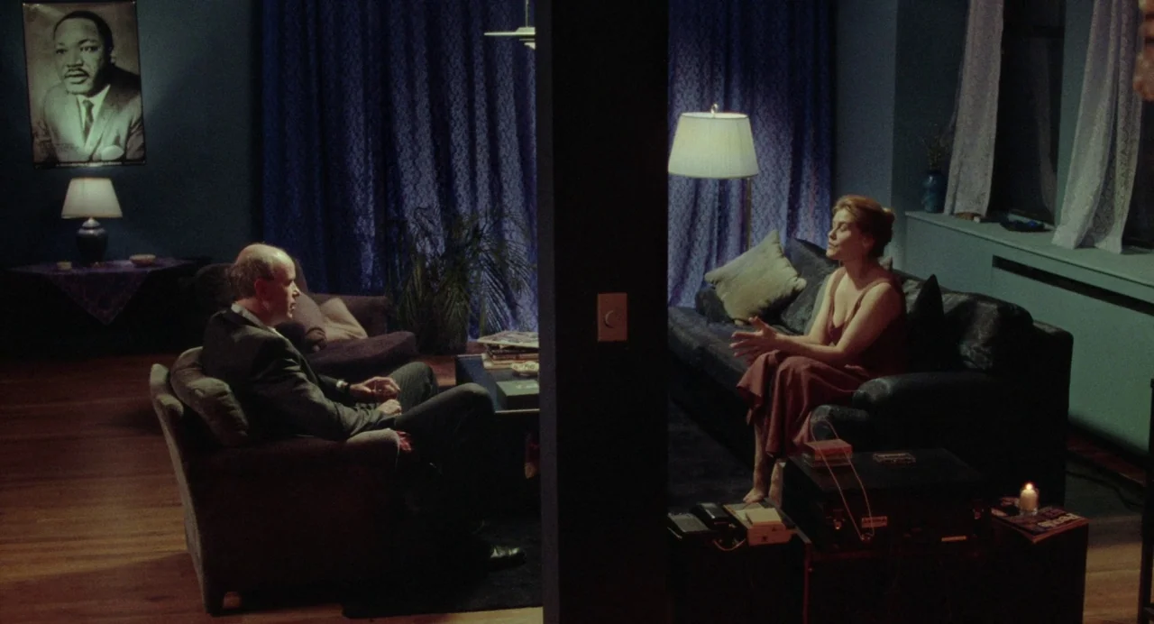 What Happened Was… (1994) movie still: wide — A dark living room features blue curtains and a portrait of Martin Luther King. A man and a woman sit…