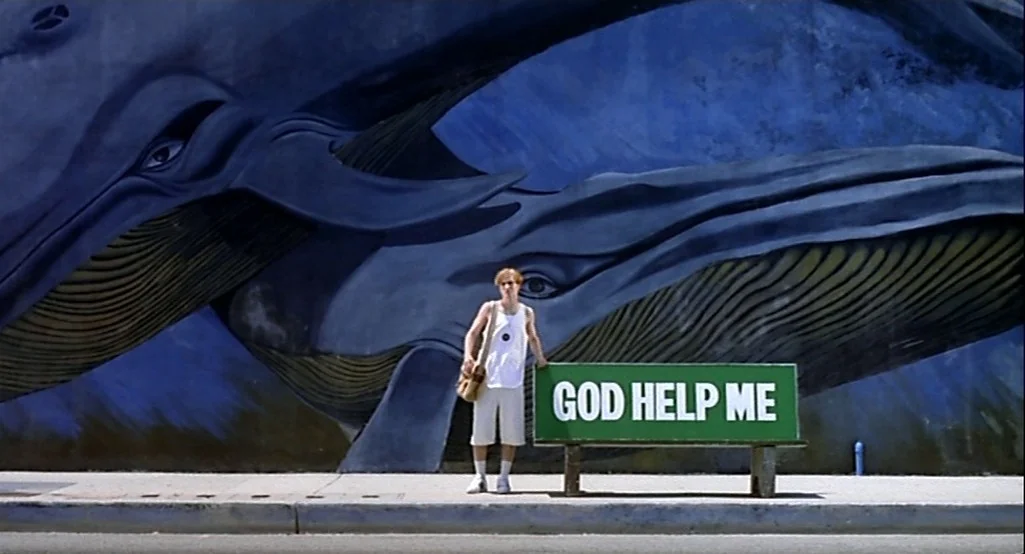 Nowhere (1997) movie still: fullbody — A mural depicting two blue whales covers a large wall behind a concrete sidewalk. A young man wearing a white…
