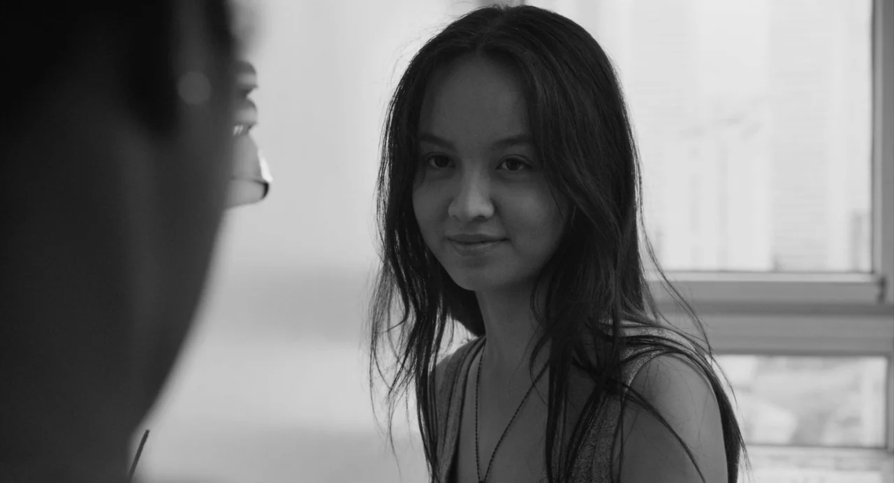Paris, 13th District (2021) movie still: closeup — A light-filled room with a window provides natural backlight to a woman's face. The woman looks…
