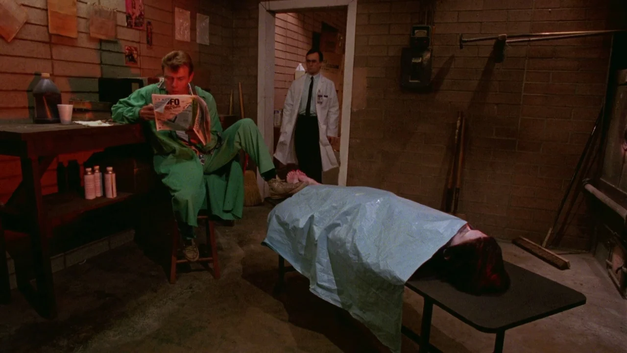 Bride of Reanimator (1989) movie still: wide — A basement with cinder block walls and exposed infrastructure housing a metal examination table. One…