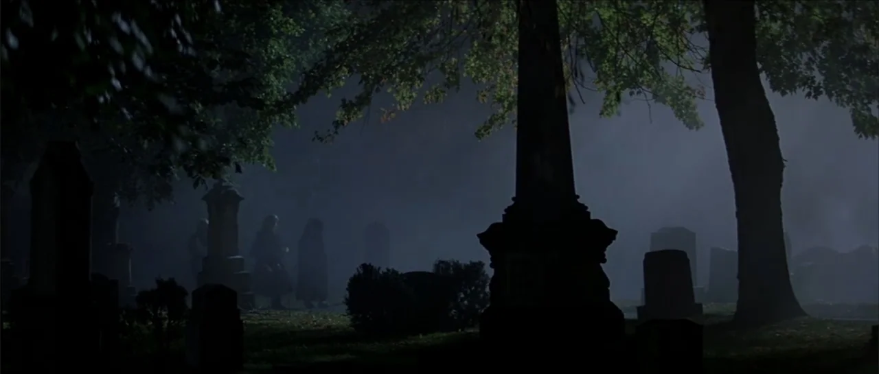 Moonlight and Valentino (1995) movie still: wide — A dark cemetery at night features thick fog weaving between weathered stone monuments. Large…