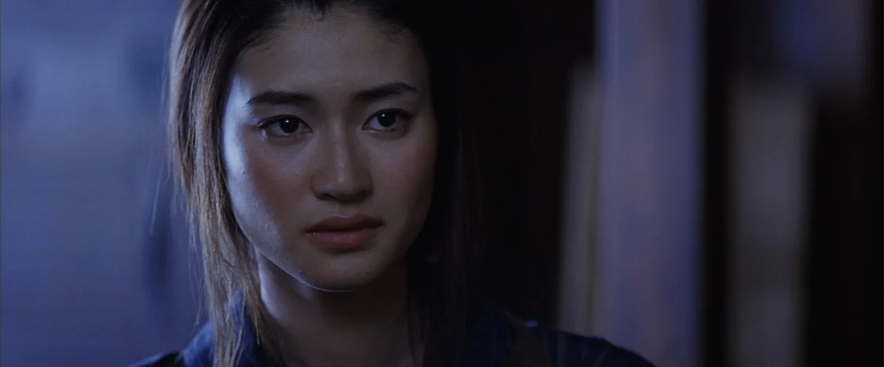 The Last Samurai (2003) movie still: closeup — A dimly lit interior space with shadows obscuring the surroundings. A young woman with dark hair…