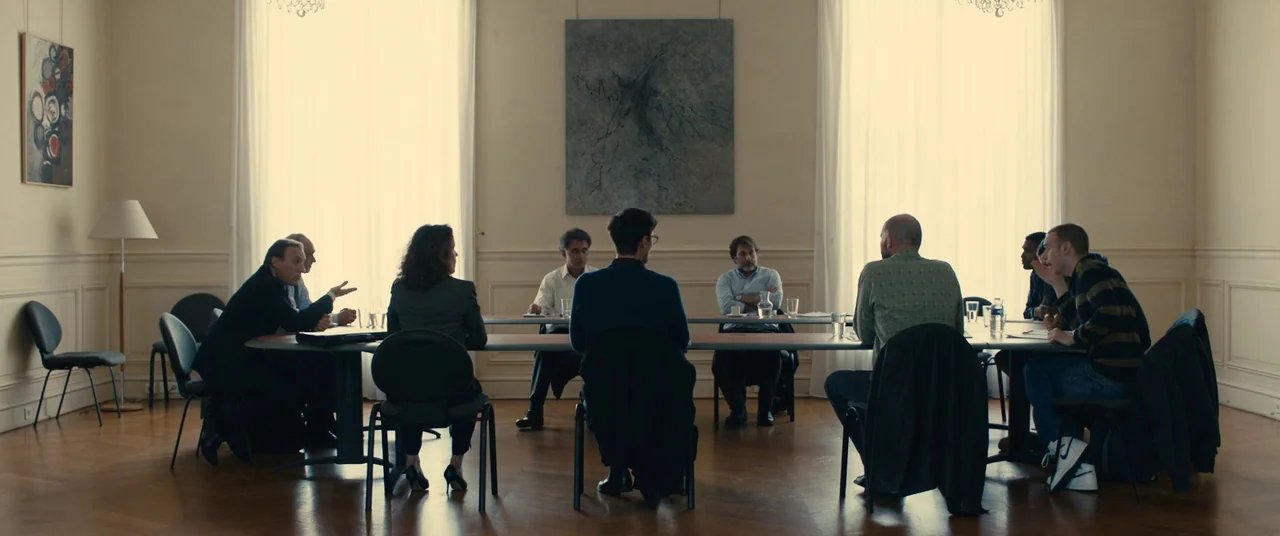 BPM (Beats Per Minute) (2017) movie still: wide — A spacious meeting room features minimalist decor and large windows covered with sheer curtains.…