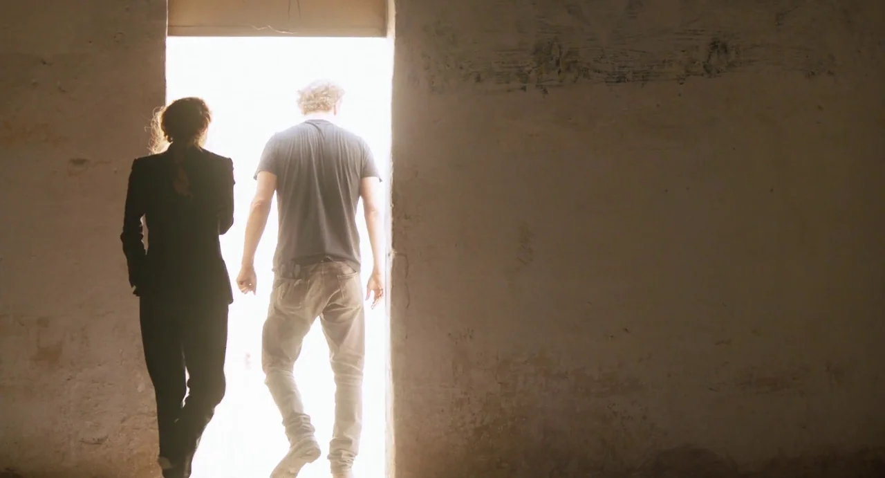 Zero Dark Thirty (2012) movie still: fullbody — An interior space with rough plaster walls transitions to a bright, sunlit outdoor area. Two…