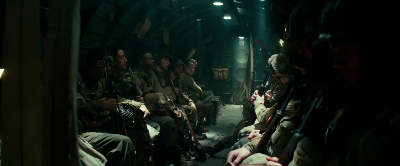 Overlord (2018) movie still: wide — The interior of a military transport plane shows a narrow, arched metal cargo bay. Multiple soldiers in full…