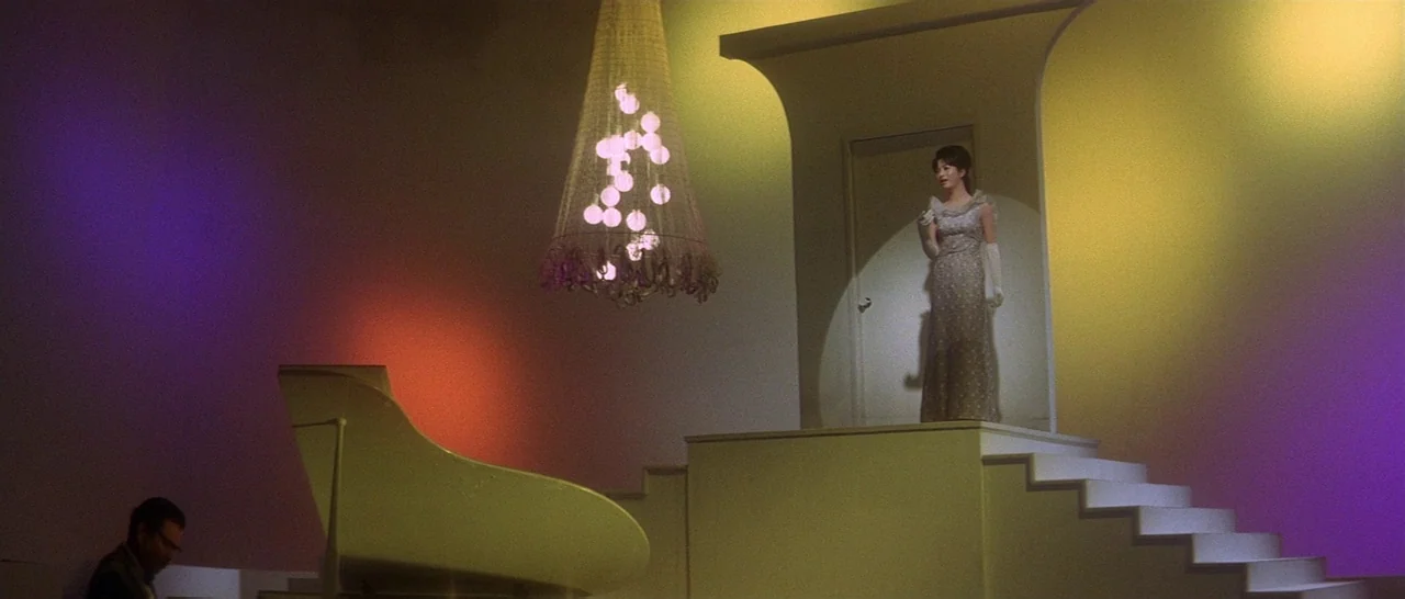 Tokyo Drifter (1966) movie still: wide — A minimalist studio stage set features a white grand piano and a central staircase. A female performer…