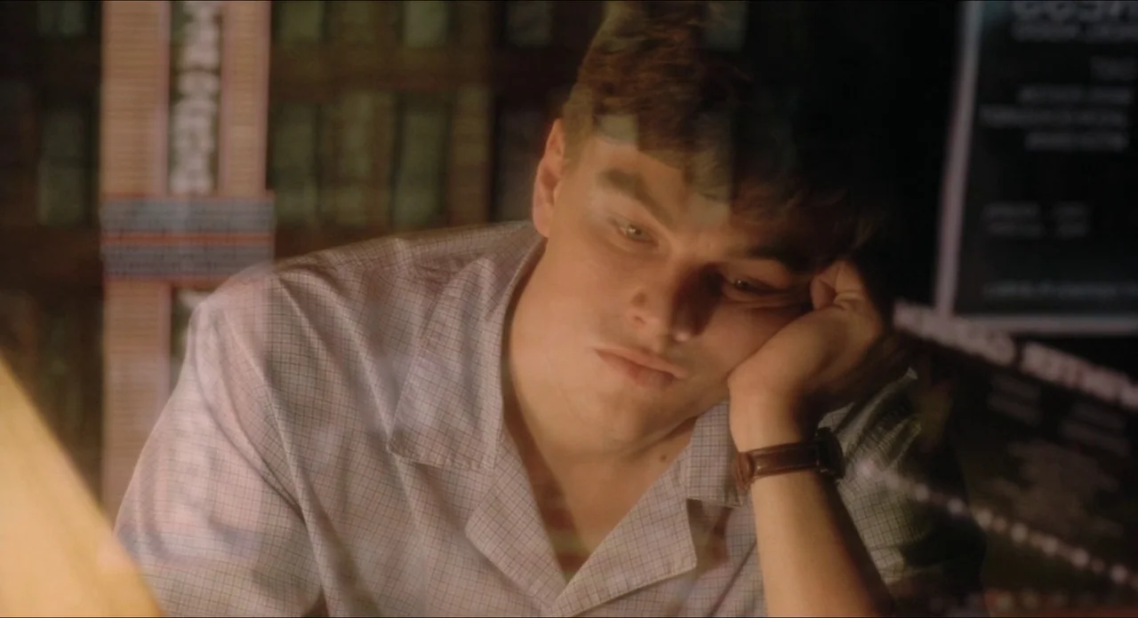 Catch Me If You Can (2002) movie still: closeup — A dimly lit library interior features wooden bookshelves in the background and a person. A young…