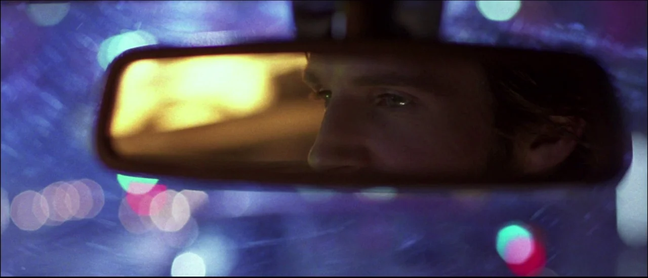 Strange Days (1995) movie still: closeup — A man's eyes and forehead are visible in the central reflective surface. Blurred city lights create a…
