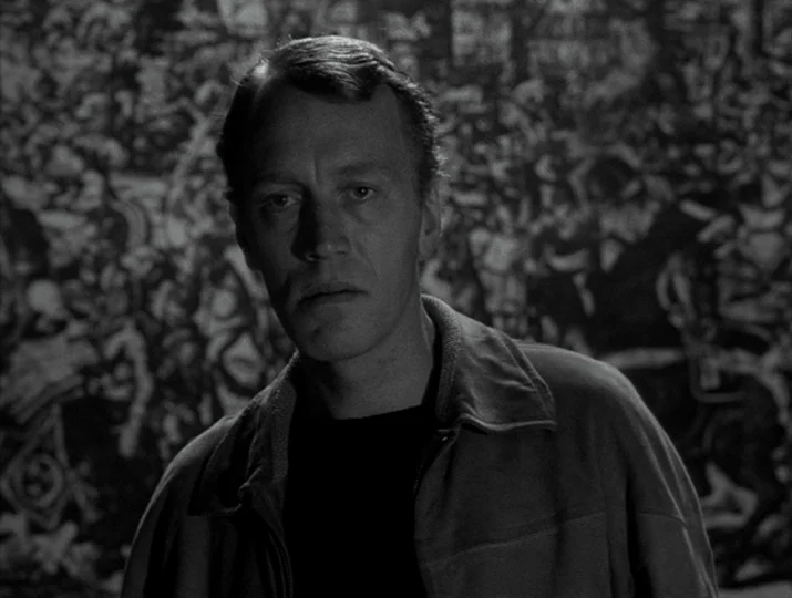 Hour of the Wolf (1968) movie still: medium — A man stands in an art gallery in front of a large, complex mural. The background artwork features…