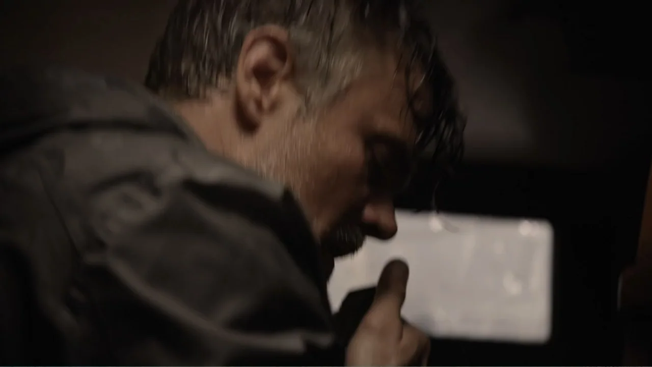Capsized: Blood in the Water (2019) movie still: closeup — A dark car interior at night with limited ambient light. A man in a dark jacket watches a…