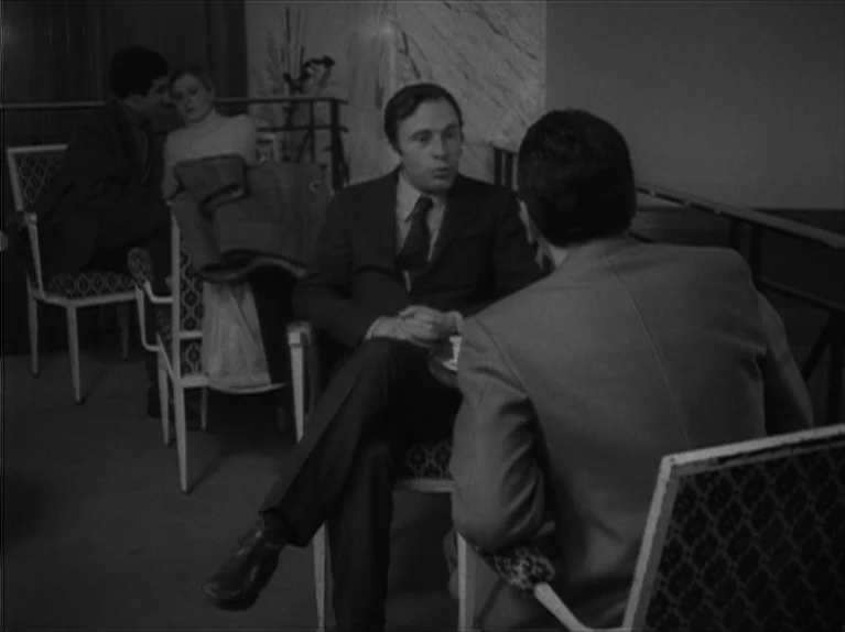 My Night At Maud’s (Ma Nuit Chez Maud) (1969) movie still: medium — An interior cafe space features patterned upholstered chairs and a…