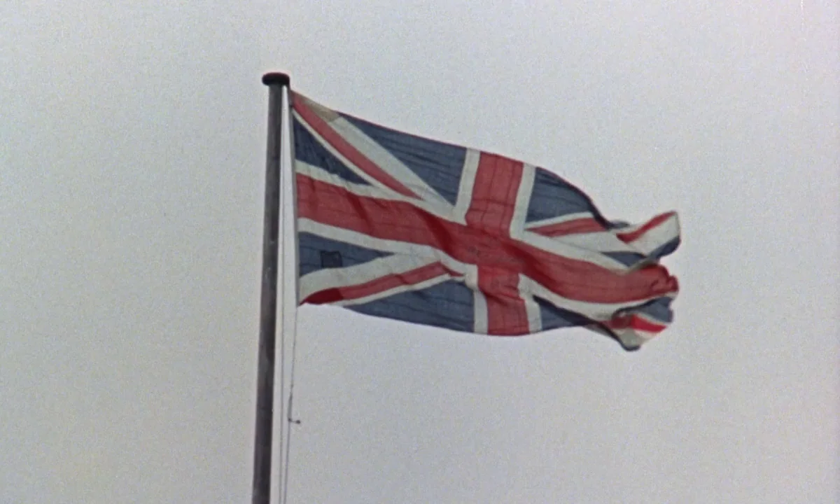 If…. (1968) movie still: medium — A United Kingdom flag hangs from a tall, thin flagpole against a featureless sky. The fabric of the flag shows…