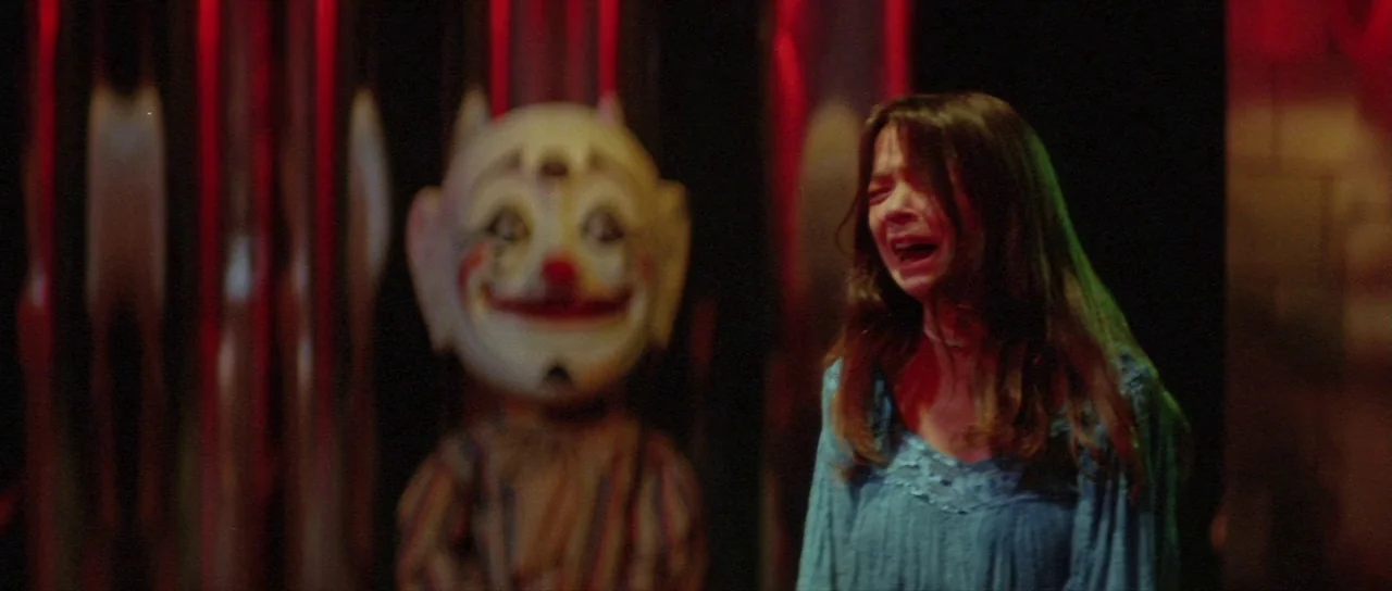 The Funhouse (1981) movie still: medium — A dark indoor space features a wall of metallic red vertical strips. A young woman cries while standing…