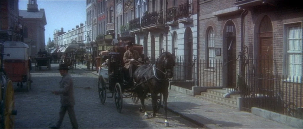 The Private Life of Sherlock Holmes movie still: wide — A nineteenth-century cobblestone street is lined with multi-story Victorian brick row…