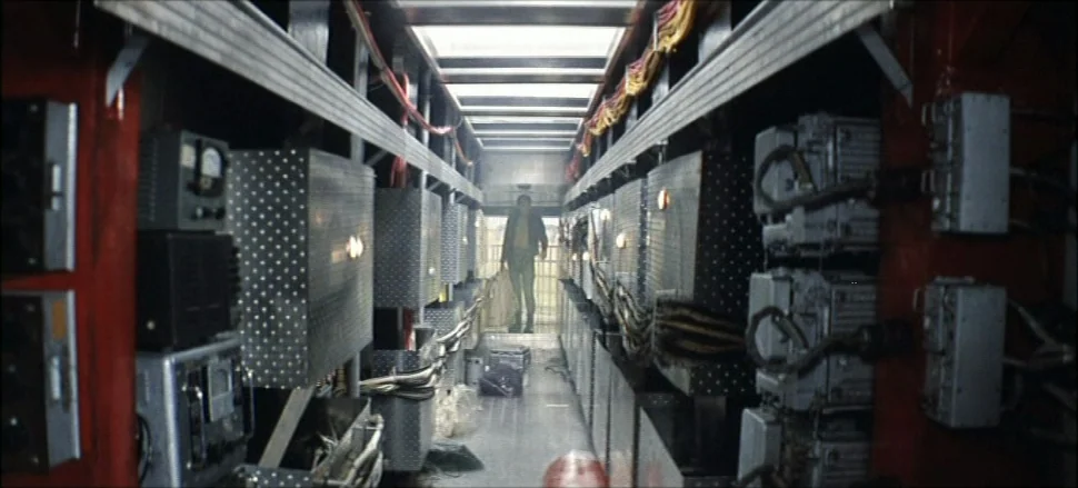 Solaris (1972) movie still: wide — A narrow service corridor lined with metallic boxes and complex electronic cabling systems. A man walks forward…
