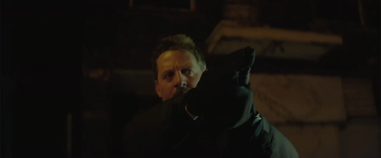 Queen & Slim (2019) movie still: medium — A dark urban alleyway at night serves as the setting for an encounter. A middle-aged man aims a handgun…