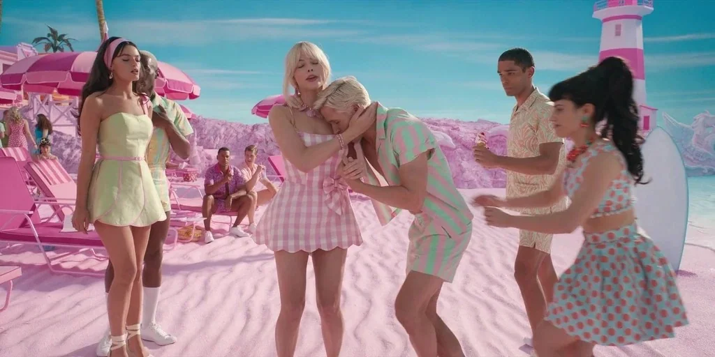 Barbie (2023) movie still: fullbody — A surreal beach setting with bright pink sand and a toy-like aesthetic. A couple stands in the foreground…