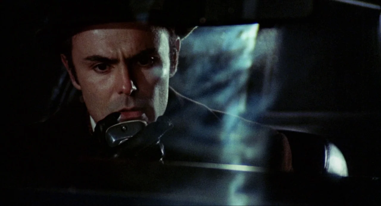 Black Christmas (1974) movie still: closeup — A dark, cramped interior of a 1970s automobile at night. A man speaks into a handheld police-style…