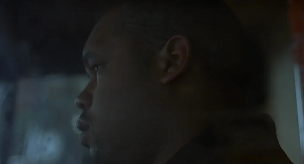 Vendredi Soir (2002) movie still: closeup — A man sits inside a dark vehicle looking out the window at night. The dim light casts deep shadows…