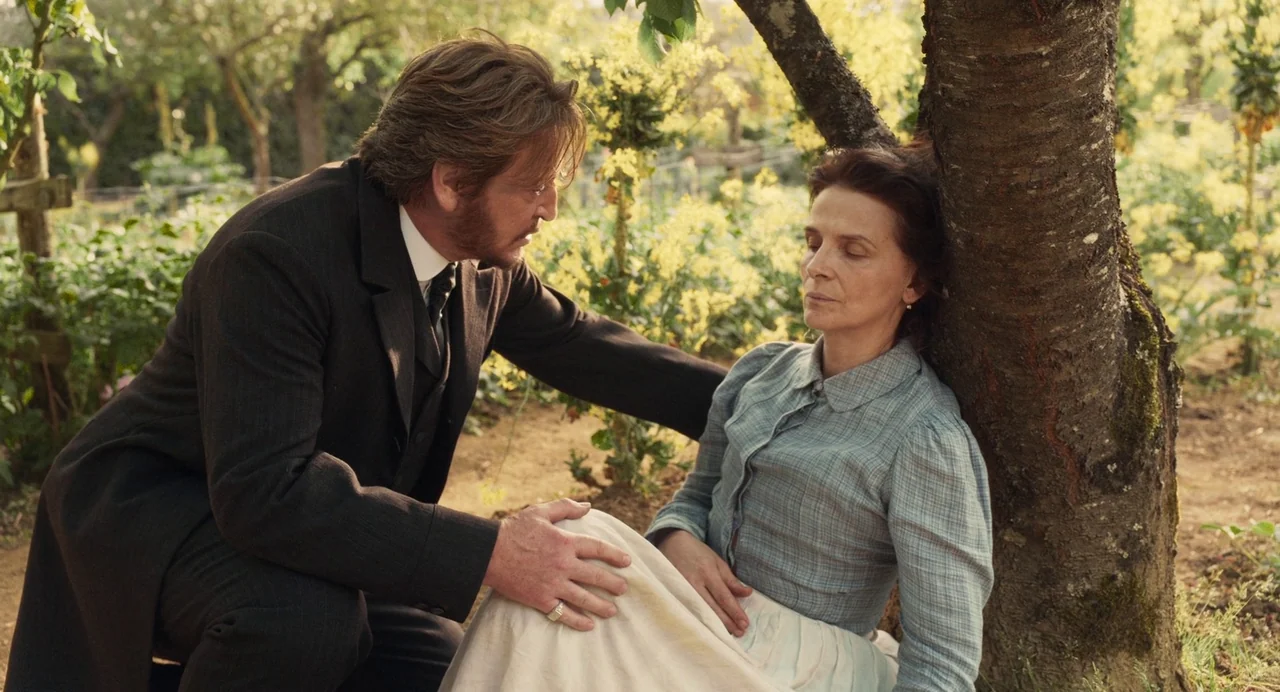 The Taste of Things (2023) movie still: medium — A rural orchard filled with leafy trees and yellow flowers under diffuse daylight. A man in a suit…