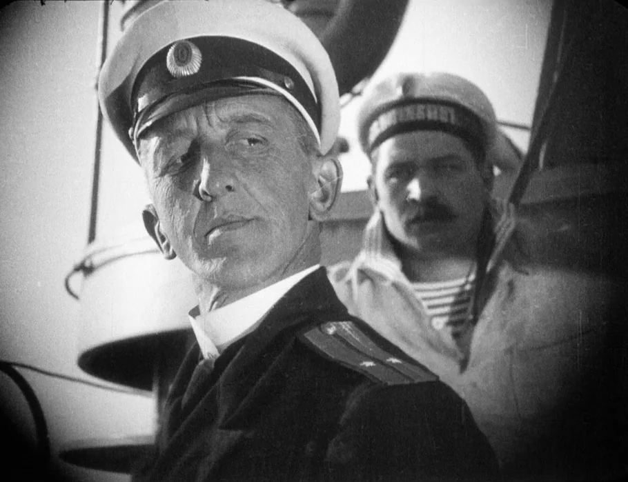 Battleship Potemkin (1925) movie still: medium — A ship deck with metal structural elements visible in the background and foreground. Two men in…