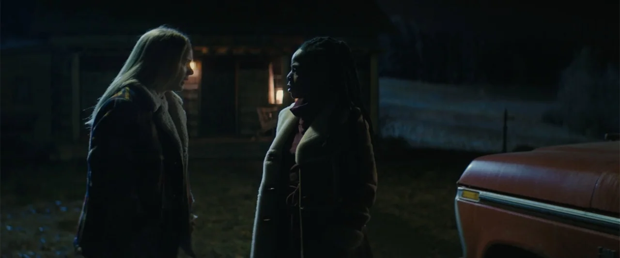 I'm Your Woman (2020) movie still: medium — A rural dark space outside a small structure at night with a vehicle nearby. Two women are positioned in…