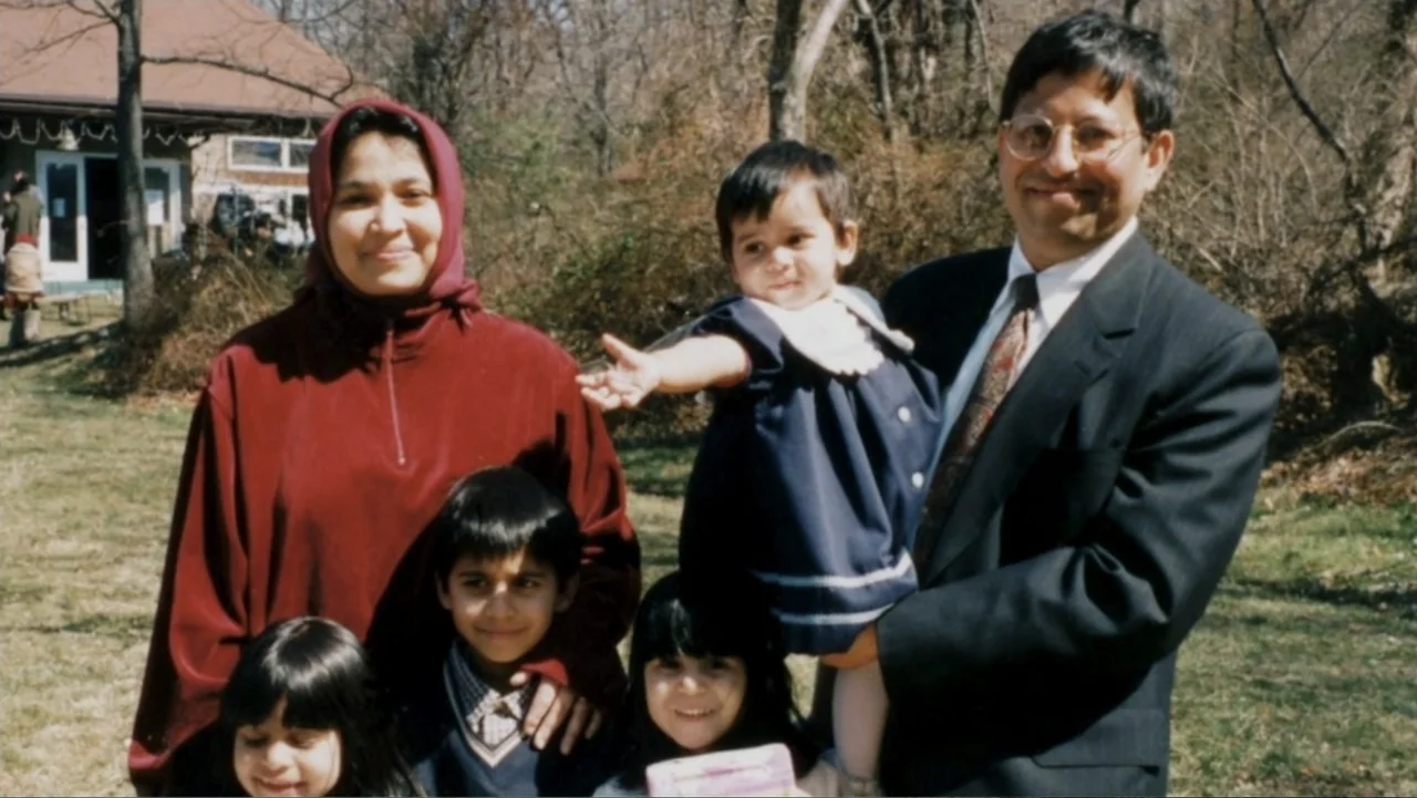 In the Shadow of the Towers: Stuyvesant High on 9/11 (2019) movie still: medium — A family stands together on a grassy lawn with a house in the…