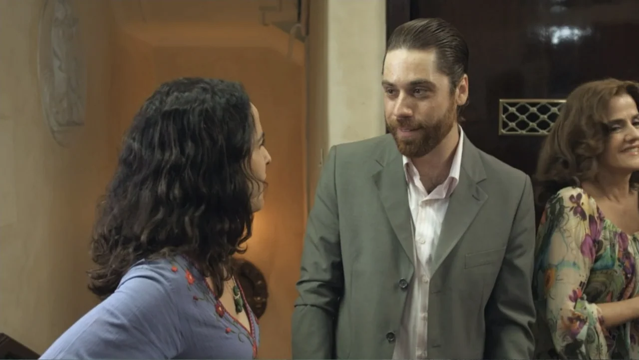 For Sale or Rent (2013) movie still: medium — An interior space features walls painted in warm earth tones and a dark wooden door. A man in a suit…