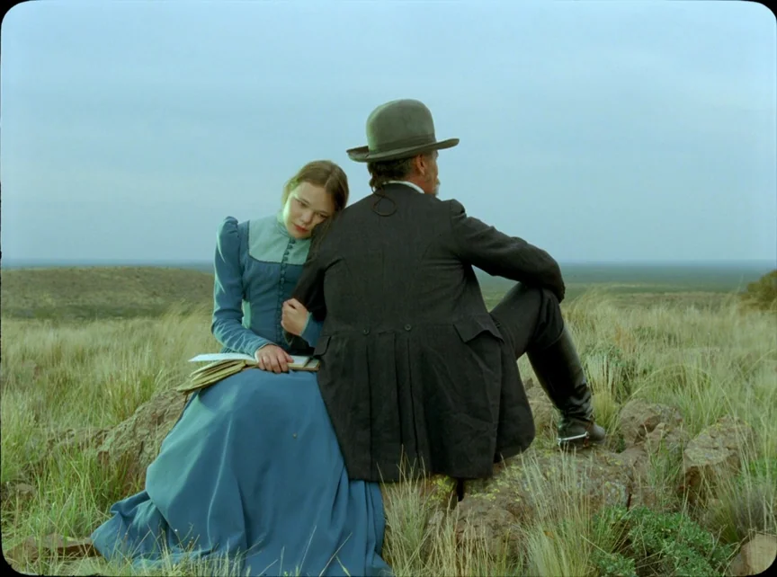 Jauja (2014) movie still: fullbody — An open grassy field under an overcast, pale sky stretches to a distant horizon. A woman in a blue dress rests…