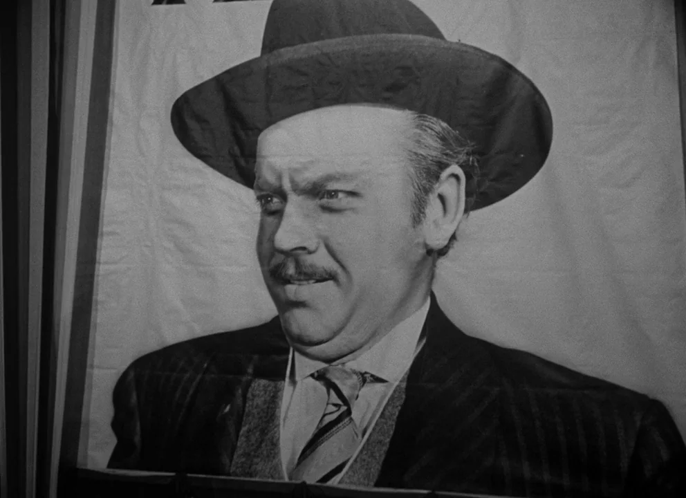 Citizen Kane (1941) movie still: closeup — A close-up view of a printed poster featuring a man in a hat. The image shows the man from the chest up…