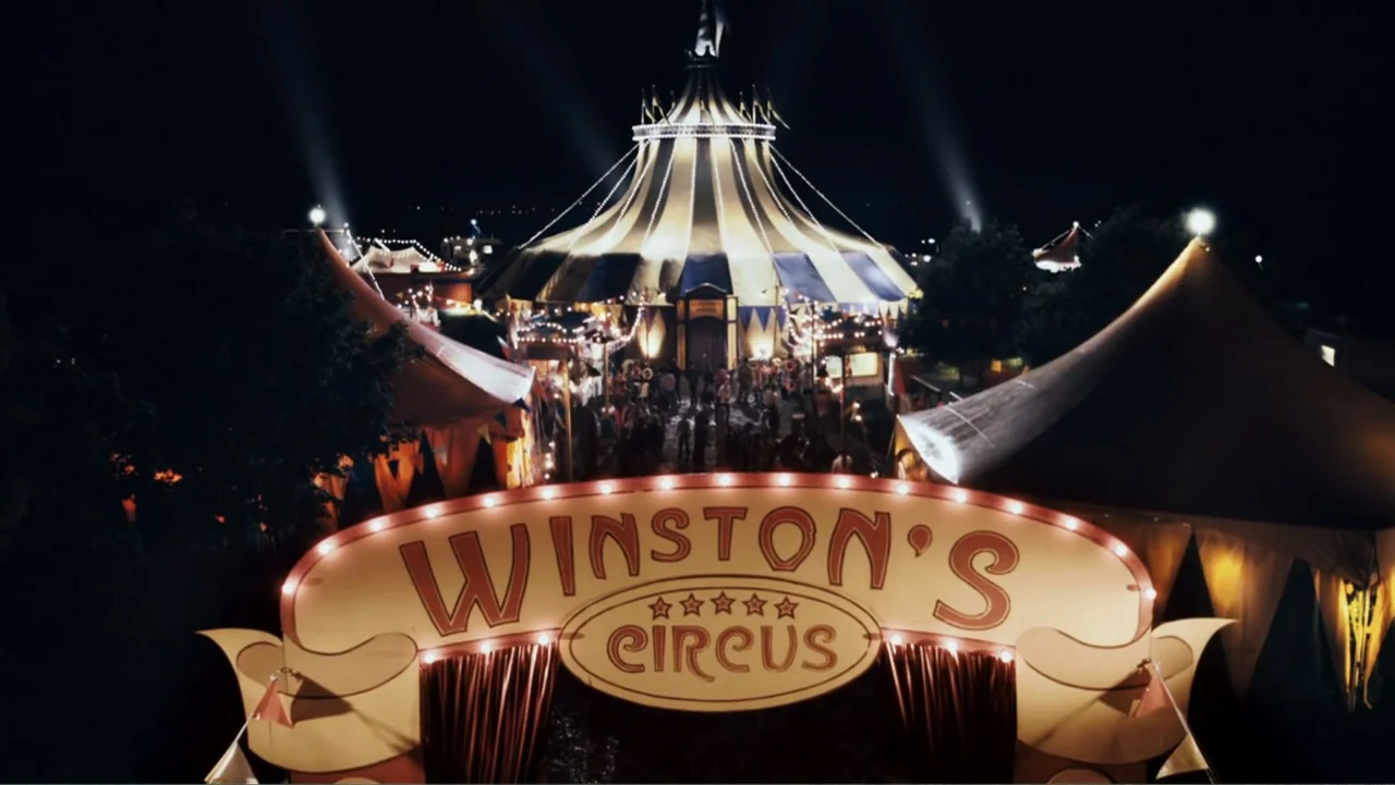 Sophie & Sheba (2010) movie still: establishing — A large striped circus tent stands illuminated at night behind a decorative entrance sign. People…