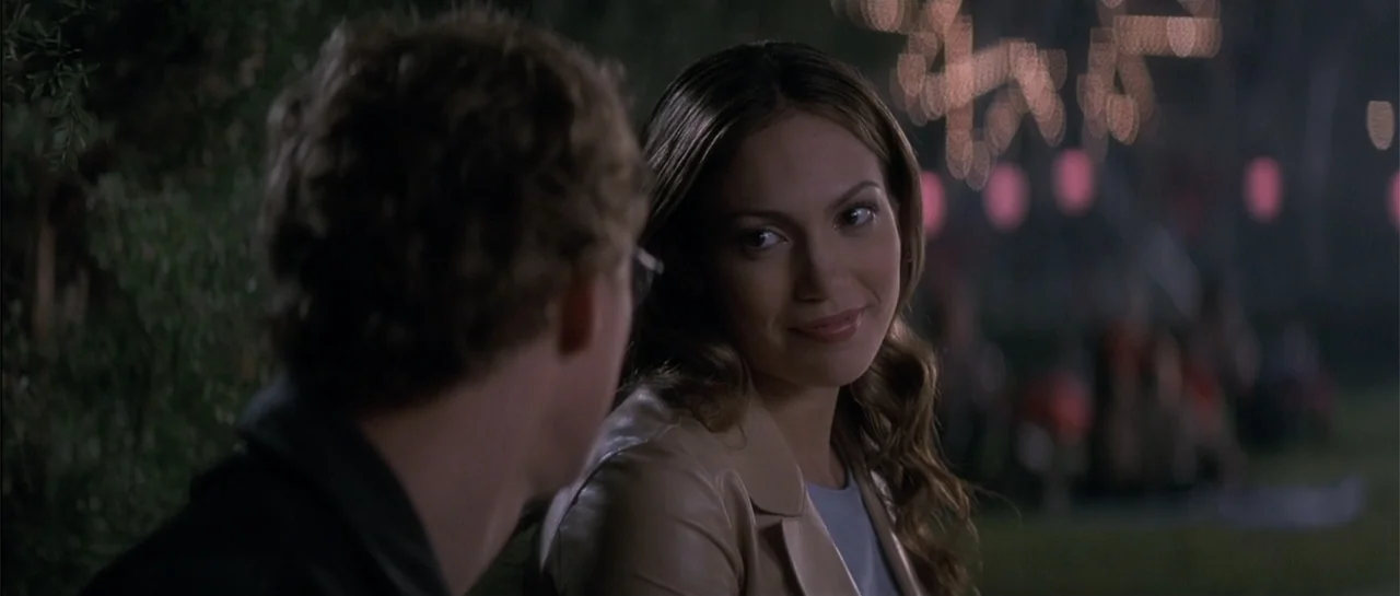 The Wedding Planner (2001) movie still: medium — A woman and a man converse in an outdoor park area at night. The man sits facing the woman while…