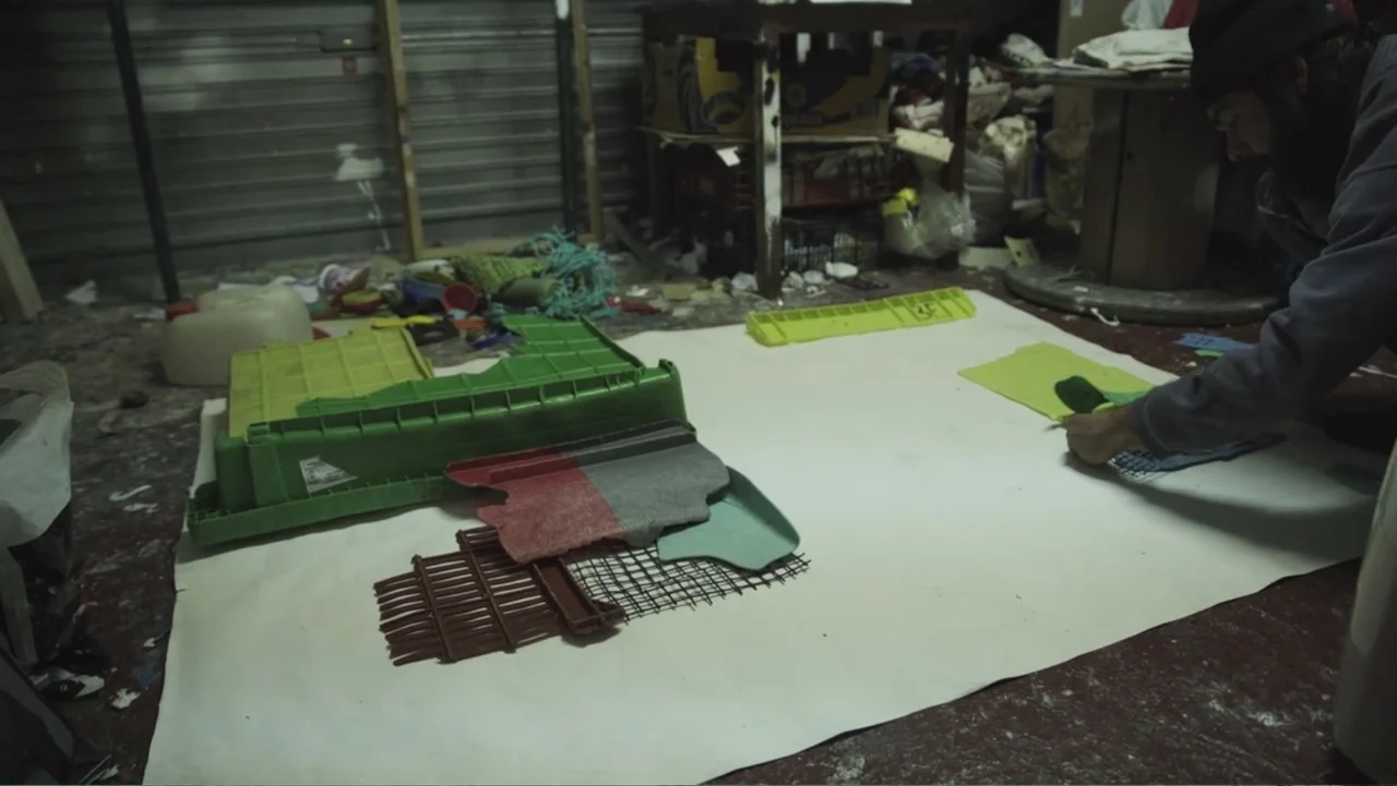 Hondar 2050 (2018) movie still: medium — A cluttered workshop interior features various industrial materials and plastic components scattered about.…
