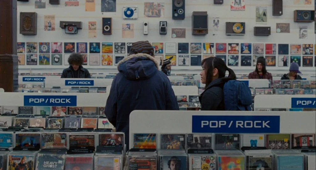 Scott Pilgrim Vs The World (2010) movie still: medium — A well-lit music store features long white shelving units organized with numerous CD cases.…