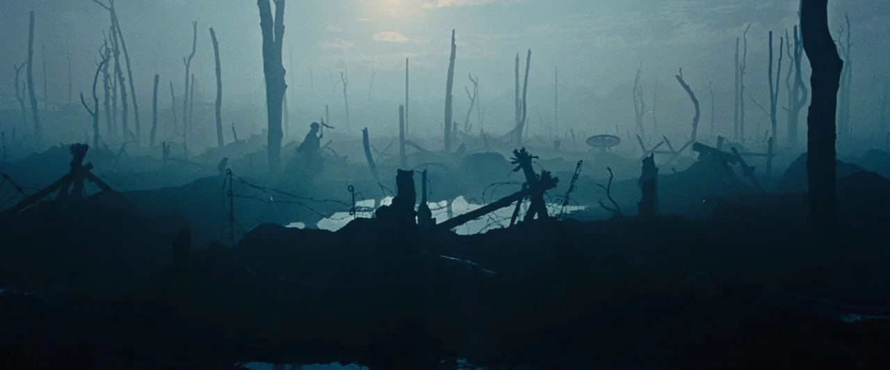 War Horse (2011) movie still: wide — A war-torn landscape covered in thick fog features jagged tree stumps and muddy trenches. Barbed wire remnants…