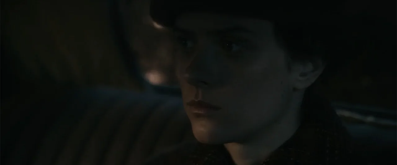 Freud's Last Session (2023) movie still: closeup — The interior of a vehicle at night with dark, indistinct upholstery. A woman wearing a beret and…