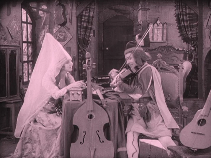 Making of: The Wheel (La Roue) (1923) movie still: fullbody — A stone-walled interior with a high-pointed arch doorway and various stringed…
