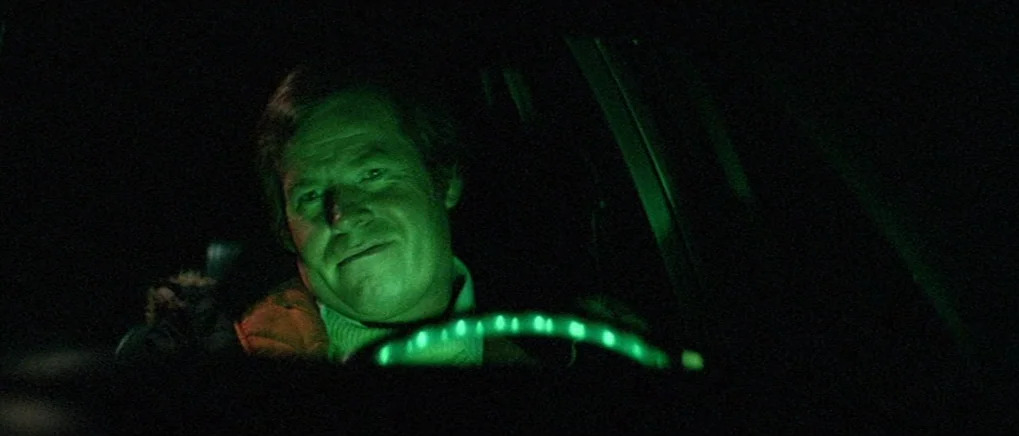 The Fog (1980) movie still: closeup — The interior of a 1970s vehicle is submerged in total darkness. A man sits behind the steering wheel…