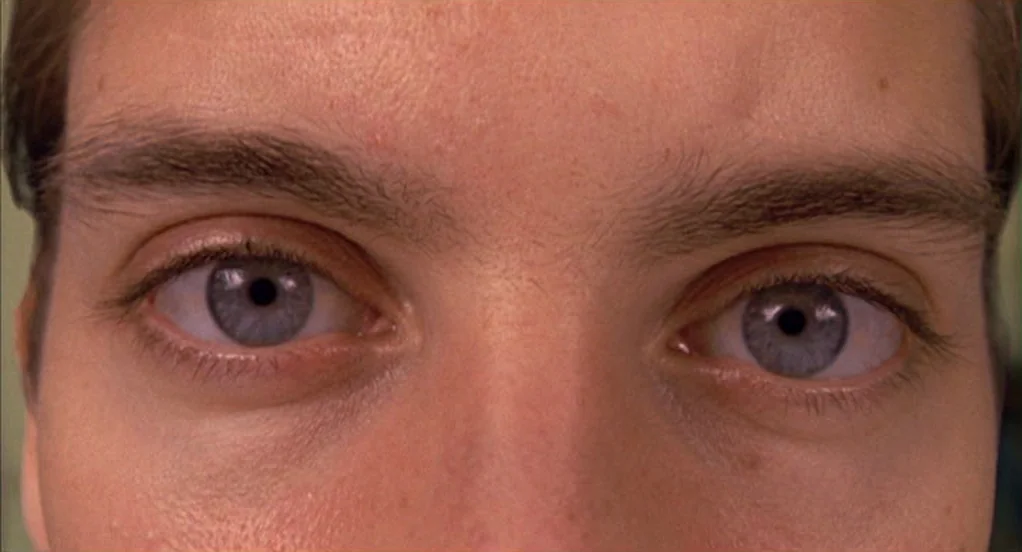 Spider-Man (2002) movie still: closeup — A close-up view shows a person's upper face, focusing on their eyes. The skin texture is visible, including…