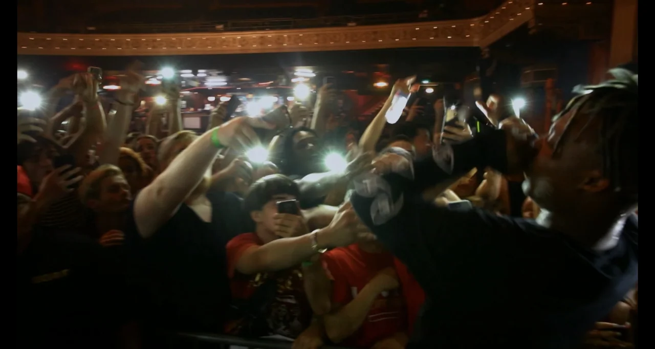 Juice WRLD: Into the Abyss (2021) movie still: medium — A dark, crowded concert venue is illuminated by many glowing smartphone screens held up. A…
