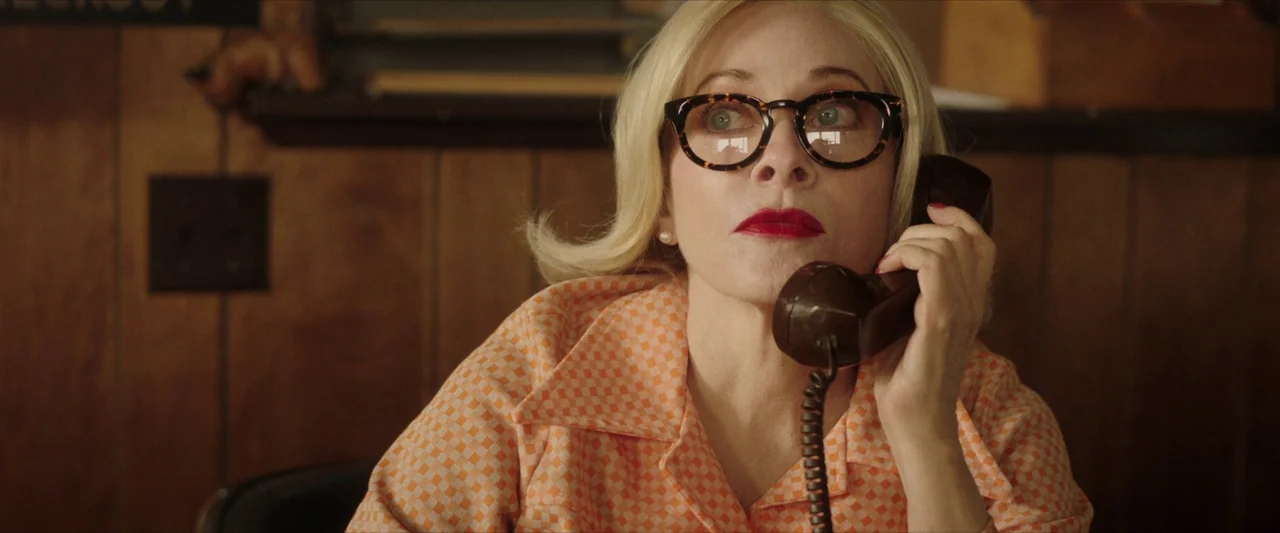 The Last Stop in Yuma County (2023) movie still: closeup — A wood-paneled room with brown wall texture is visible behind the woman. The woman talks…