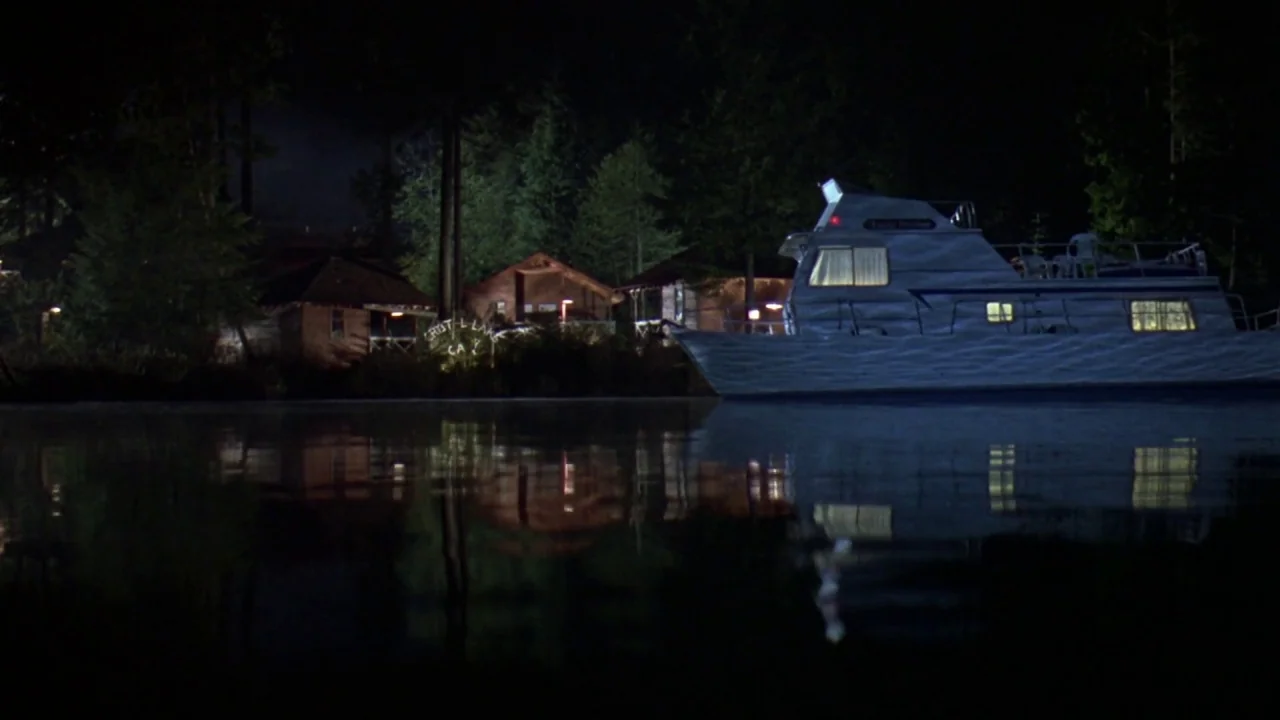 Friday the 13th Part VIII: Jason Takes Manhattan (1989) movie still: wide — A boat floats on a dark, calm lake at night with cabins visible on…