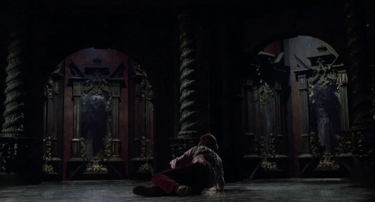 Etoile (1989) movie still: wide — A dark, ornate hall features multiple tall mirrors set within carved, dark-colored architectural columns. A man…